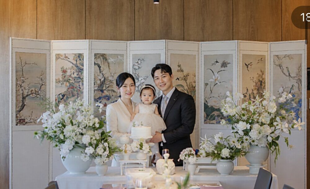 돌잔치 출장상차림 현장 - 전통 병풍과 흰 생화 장식 앞에서 찍은 가족사진